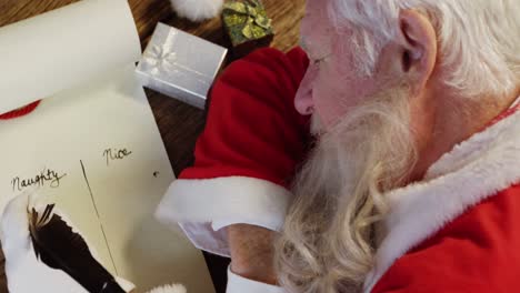 santa claus durmiendo en el escritorio mientras escribe una carta con una pluma