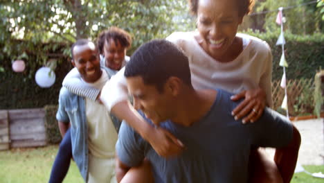 two young adult black couples having fun piggyback in garden