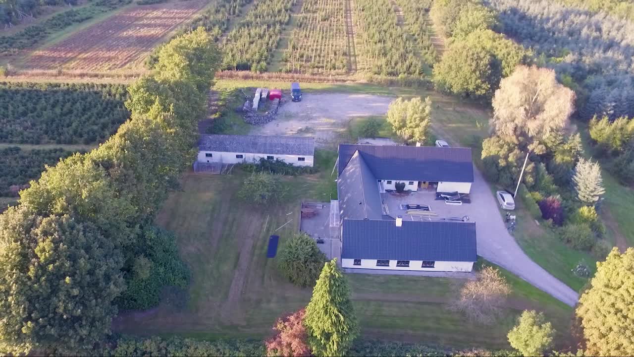 Aerial video orbit around a farm during sunset.