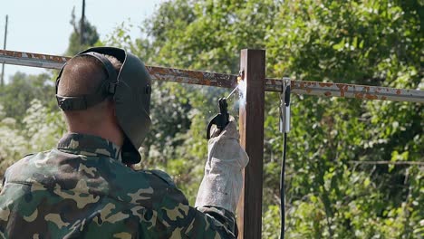 el hombre suelda el cadáver de la valla en los árboles en cámara lenta vista trasera