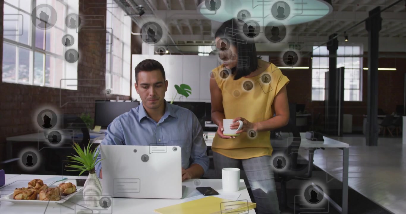 Donna che si avvicina per esaminare il laptop con un collega in ufficio, mentre digita e le icone UI fluttuano sopra i due