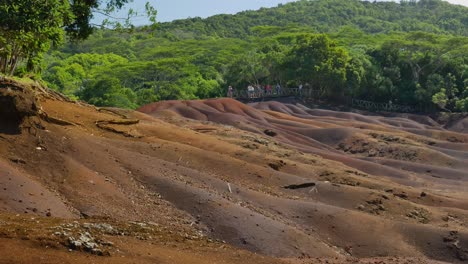 A-panning-of-multicolored-sand,-with-many-people-watching-from-a-viewpoint-at-the-background