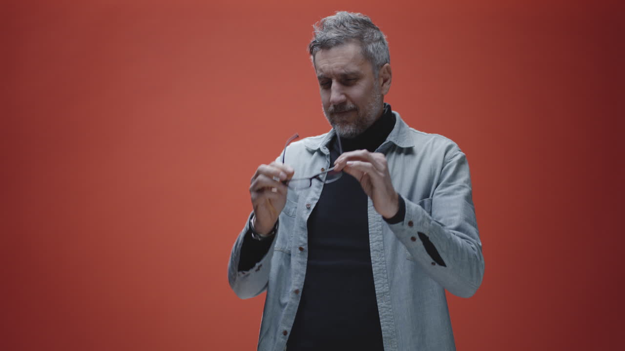 Man adjusting shirt and clapping hands in front of red background