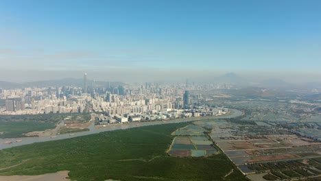 Hong-Kong-and-Shenzhen-border-line-over-Hong-Kong-rural-houses-with-Shenhzen-skyline-in-the-horizon,-Aerial-view