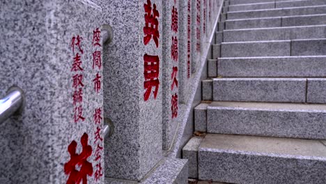 Slow-motion-walk-up-next-to-typical-stone-pillars-with-Chinese-writing-at-temple