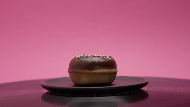 Sweet donut with black chocolate topping and colorful crumbs