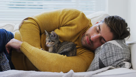 Young-man-sleeping-on-sofa-holding-his-pet-cat-in-his-arms-4K-4k