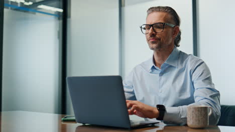 Un-Hombre-De-Negocios-Serio-Bebiendo-Té-En-El-Primer-Plano-Del-Lugar-De-Trabajo-Por-La-Noche.-Hombre-Escribiendo-Computadora-Portátil