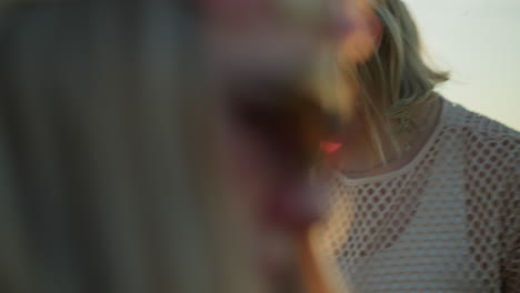 close-up of a woman, with a headband and glasses, intently focused on cleaning or inspecting something near a motorcycle helmet