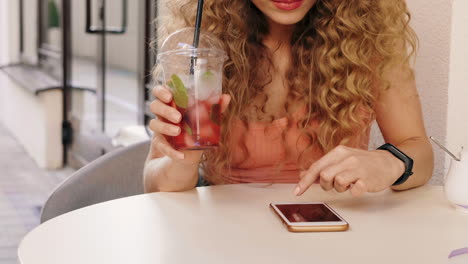 woman enjoying a drink and using her phone at an outdoor cafe