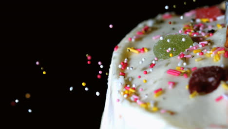 Colourful-sprinkles-pouring-onto-iced-cake-with-candy