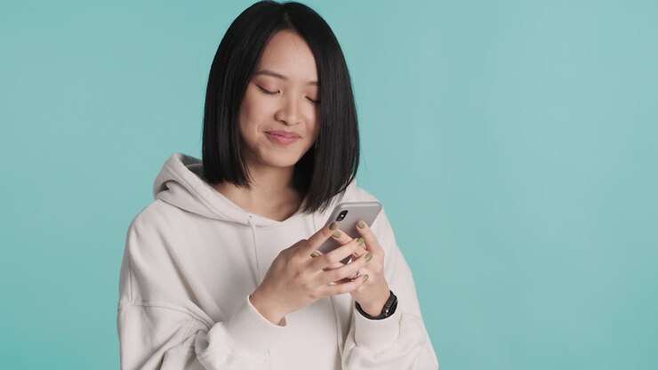 Asian woman texting on smartphone and thinking on camera.