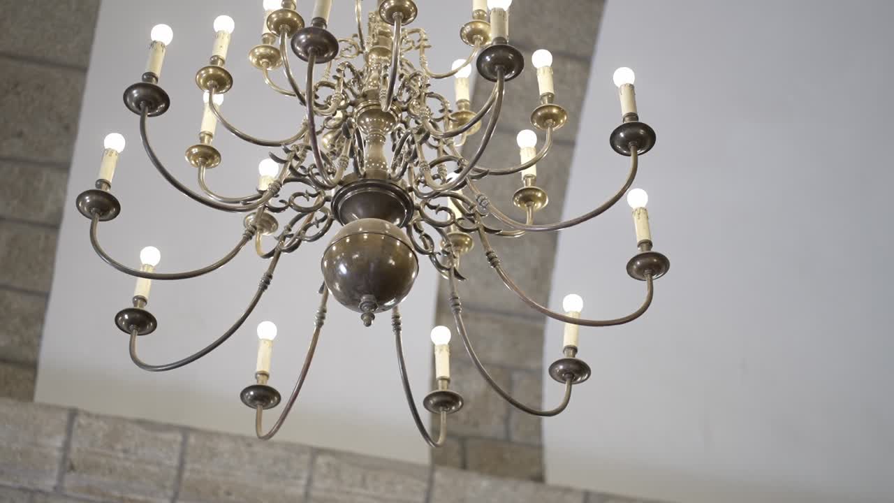 classic chandelier with lit bulbs inside arched stone ceiling space