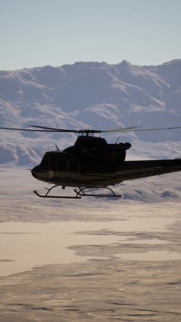 black helicopter flying over mountain range