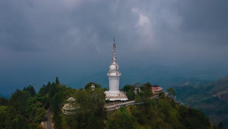 ambuluwawa tower on top of the mountain where many tourists walk over the spiral stairs  from the view point as the sunlight shifts over the attraction on a cloudy day. wide drone hyperlapse shot