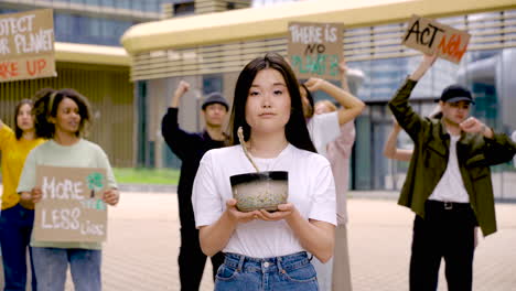 woman with board and woman with dead plant on a protest with more angry people