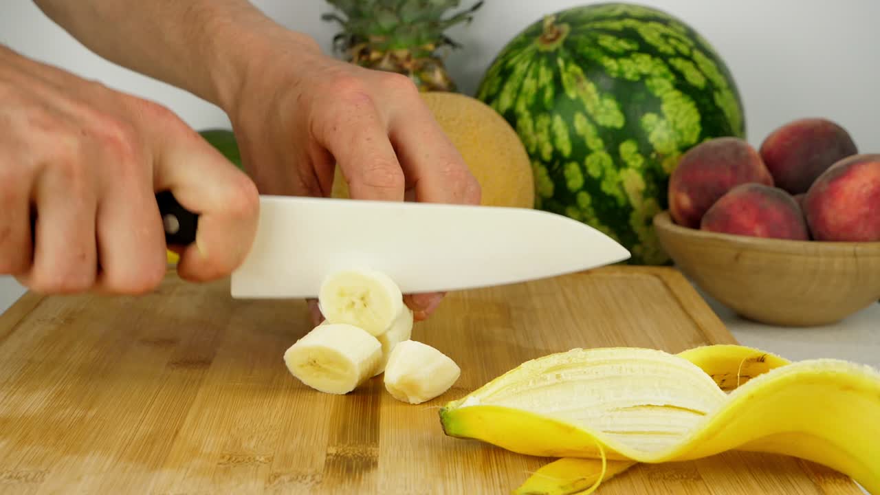cortar un plátano en una tabla de cortar de bambú, usando un cuchillo de cerámica