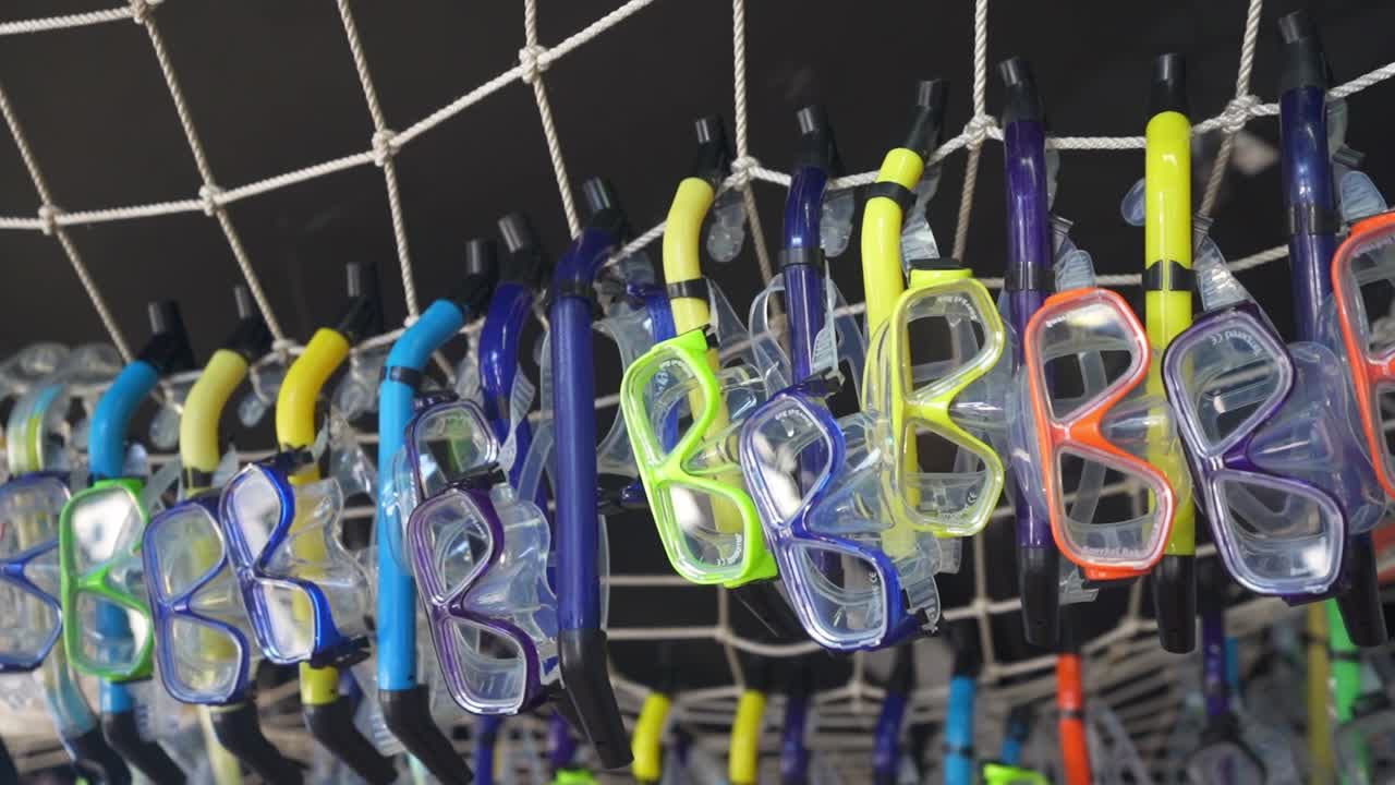 líneas de máscaras de snorkel multicolores colgando del techo en una tienda de alquiler hawaiana