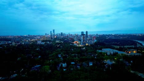 Edmonton-luxury-homes-close-to-golf-course-wildlife-river-valley-Glenora-aerial-rise-reveal-summer-twilight-overcast-glow-above-clouds-highlighting-city-skyline-lit-up-Walter-Dale-bridge-beauty-1-3YEG