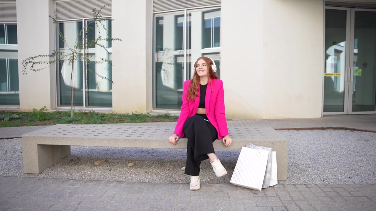 Una giovane donna alla moda, vestita con un blazer rosa e un outfit elegante, posa all'aperto.