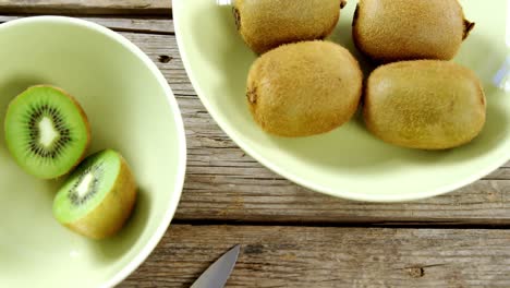 Kiwis-En-Un-Recipiente-Con-Un-Cuchillo-Sobre-Una-Mesa-De-Madera