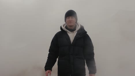 man go through dense steam cloud at myvatn geothermal area, iceland