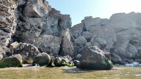 rocky coastline with waves and large boulders on a sunny day