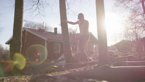 Lens-Flare-Slo-Mo---Ein-Mann-In-Den-Sechzigern,-Der-Auf-Einer-Slackline-Balanciert,-Bevor-Er-Abspringt