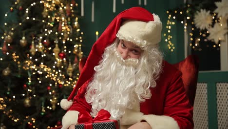 santa sits by a decorated tree holding a gift embodying joy santa claus sits in a cozy chair surrounded by a festive christmas tree full of lights he holds a wrapped gift embodying holiday joy