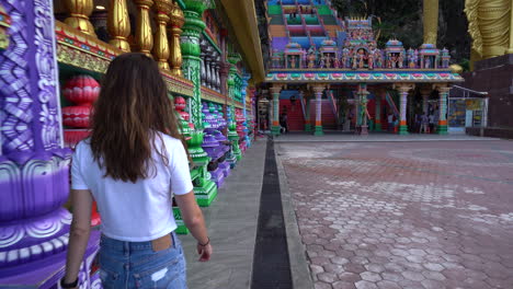 mujeres caminando hacia las cuevas de batu con la cámara inclinándose hacia arriba para revelar la escalera gigante y colorida en selangor, malasia