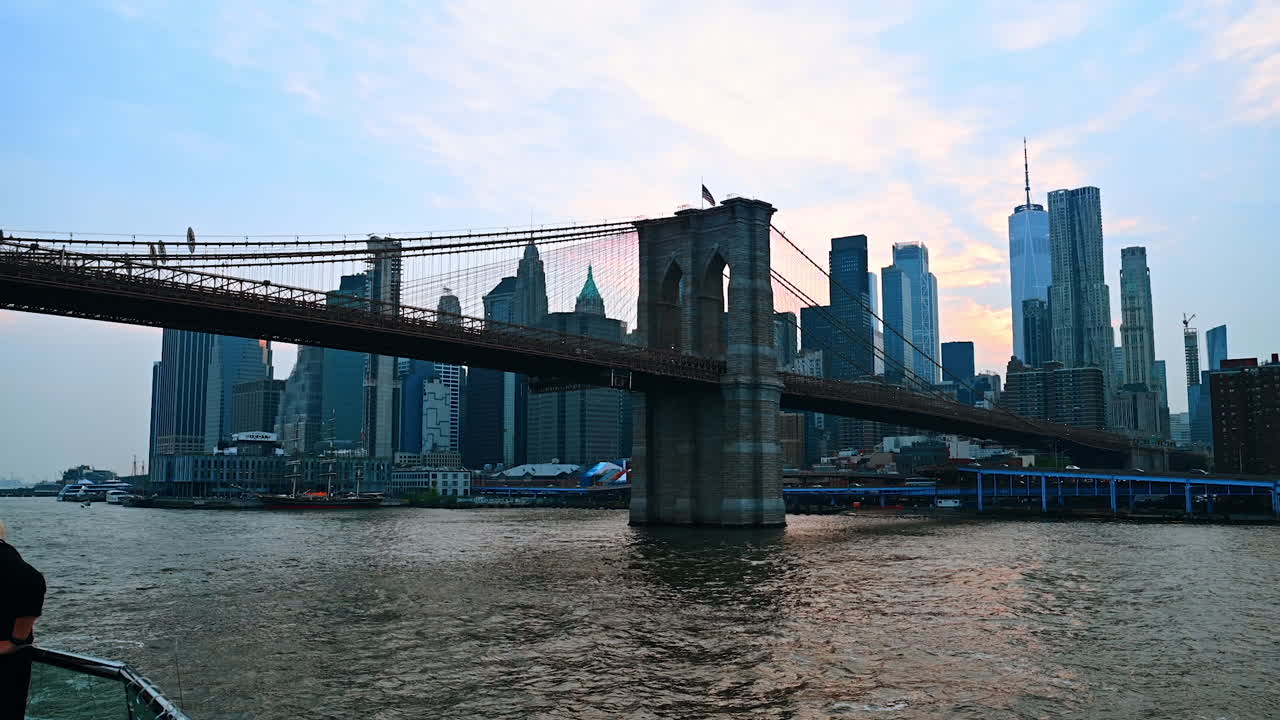 Nærmer mig Brooklyn Bridge med båden. Lav engel på det berømte vartegn i skumringen. Manhattans skyline i baggrunden.