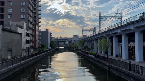 scenic canal at sunrise between modern buildings and train tracks