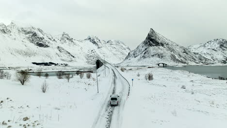 Vista-Aérea-De-La-Autocaravana-Conduciendo-Por-La-Carretera-Nevada-A-Los-Puentes-De-Fredvang-En-Invierno-En-La-Isla-De-Lofoten,-Noruega