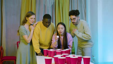 felices jóvenes amigos multiétnicos jugando al pong de cerveza en casa