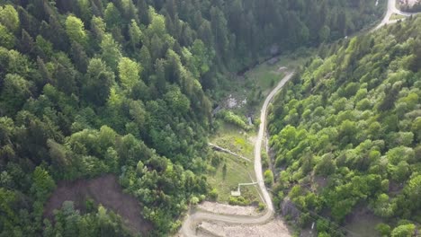 aerial panning shot of road cutting through woodland in valley