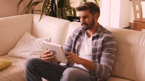 Man relaxing on sofa and using digital tablet