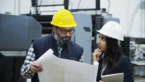 Front-view-of-printing-workers-inspecting-plan-of-building