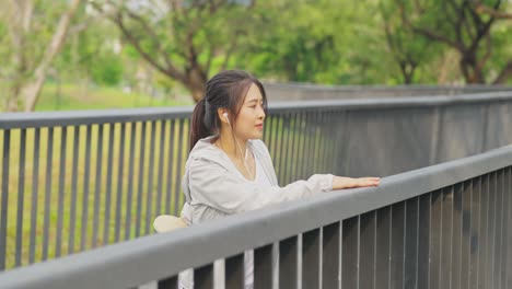 4k asian woman listening to music while jogging at public park in the morning.