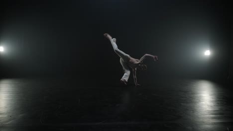 luchadores de capoeira realizando movimientos dinámicos en el escenario. artes marciales, danza y acrobacias en acción. atletas de pecho desnudo mostrando fuerza, flexibilidad y técnica bajo los reflectores