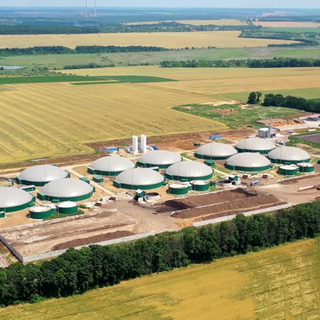 innovative plant on yellow field. biogas plant and storage tanks. construction of biogas power plant in nature. aerial view. camera moving down