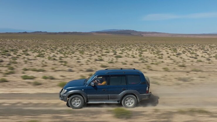 Veduta aerea di un'auto che guida su strada sterrata verso il Parco Nazionale del Canyon di Charyn in Kazakistan