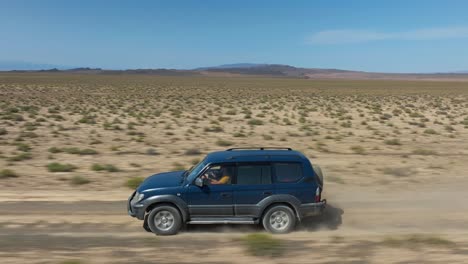 Vista-Aérea-De-Un-Viaje-En-Automóvil-Por-Una-Carretera-Sin-Pavimentar-Hacia-El-Parque-Nacional-Charyn-Canyon-En-Kazajstán