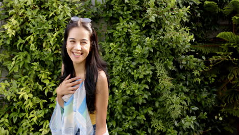 a young biracial woman smiles brightly, surrounded by lush greenery, copy space