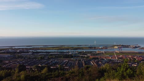 cinematic sunrise over residential houses, marina with ocean wind turbines