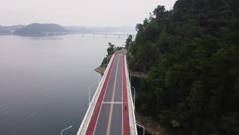 4K-Cyclist-on-Bridge-at-Qiandao-Lake,-Zhejiang-Province,-China