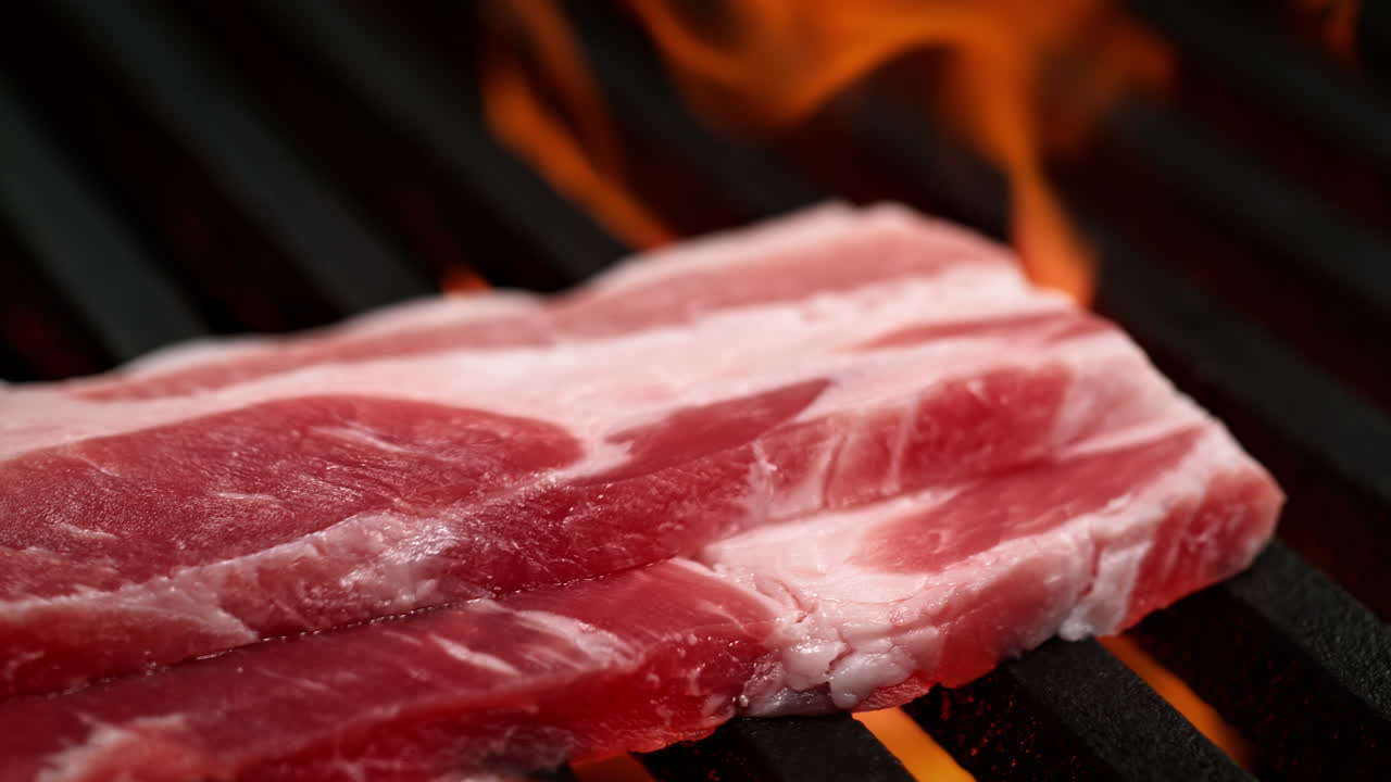 Bacon Slices Barbecued On A Grill, Roasted By The Flames Beneath The Grill Grate, Macro and Slow Motion
