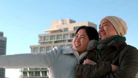 겨울 옷을 입은 사랑하는 아시아 커플이 무언가를 가리키고 있습니다.