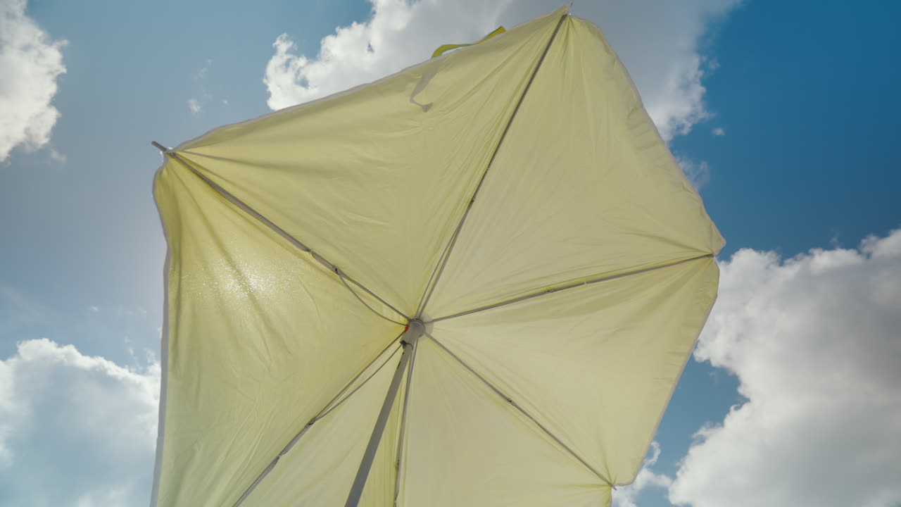 Giornata di sole sotto un ombrellone giallo da patio, cielo blu e nuvole. Perfetto per promozioni di vacanze estive
