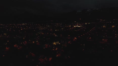 Iceland's-Akureyri-comes-to-life-in-this-4K-night-drone-shot,-city-lights-twinkling-like-stars,-a-warm-glow-against-the-enveloping-darkness