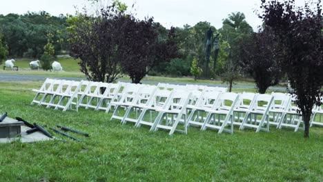 sillas plegables blancas en una boda al aire libre en un prado verde - tiro ancho